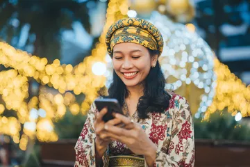 A cheerful woman in traditional clothing using her smartphone during a festive moment, showing how easily the CD33 app fits into everyday life.