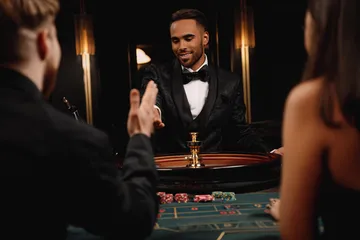 A professional dealer in a tuxedo greeting players at the roulette table, symbolizing the authentic live casino feel at CD33.