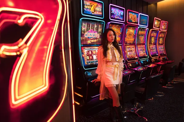 A stylish woman beside vibrant slot machines displaying glowing sevens, showcasing the variety of top slots at CD33.
